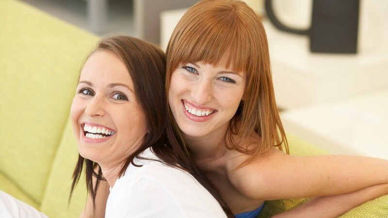 Zwei lachende Frauen sitzen auf der Couch