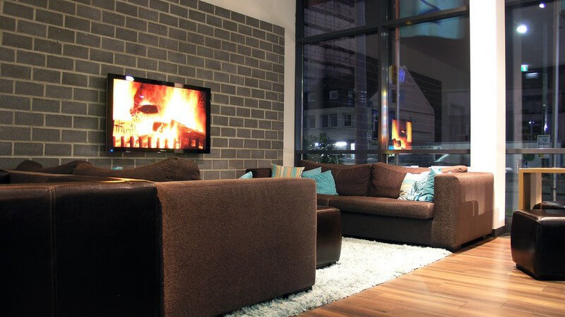 Modernes Wohnzimmer mit braunen Sofas, Kaminfeuer im Bildschirm