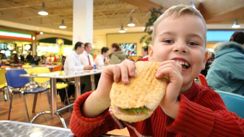 Fast Food Restaurant, kleiner Junge isst Burger