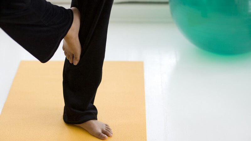 Beine einer dunkelhäutigen Frau, Yoga-Übung auf Gymnastikmatte