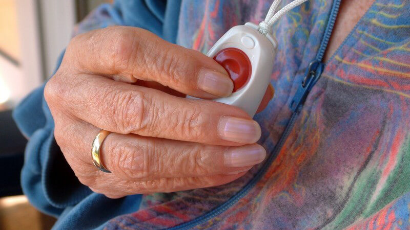 Nahaufnahme Rentnerin drückt roten Knopf auf Gerät um ihren Hals für Hilfe