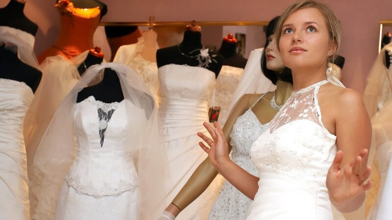 Junge Frau in Brautkleid mit Spitze in Brautmodengeschäft mit Schaufensterpuppe in Hintergrund