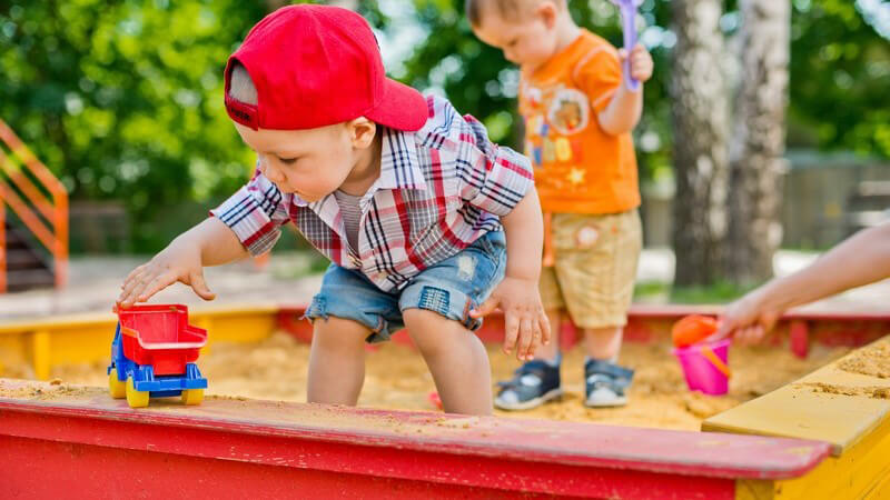 Zwei kleine Jungen spielen in einem roten Sandkasten