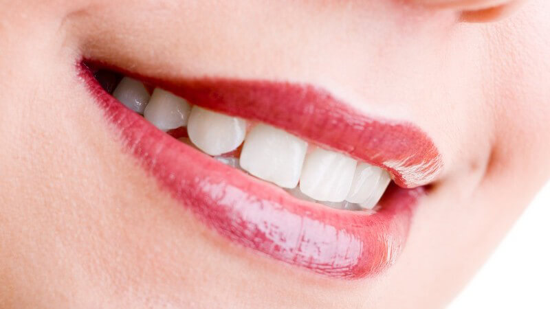Lächeln einer Frau mit roten Lippenstift und sehr weißen Zähnen