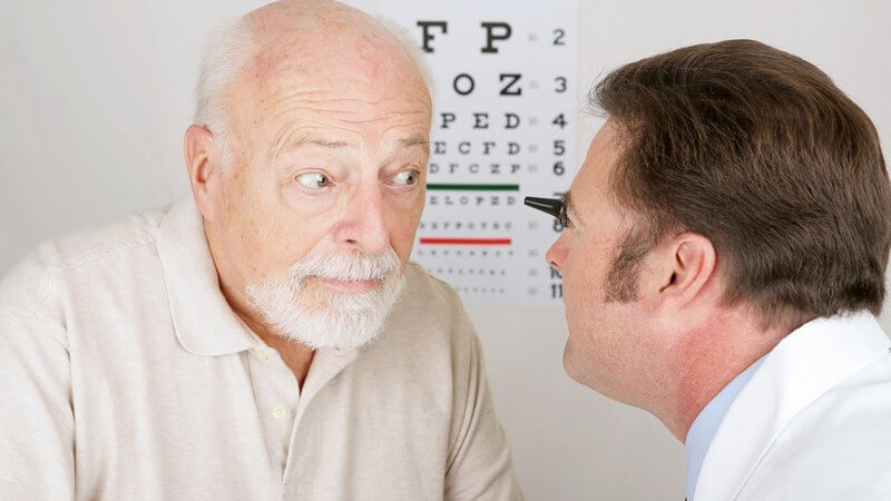 Augenarzt untersucht Auge eines älteren Mannes
