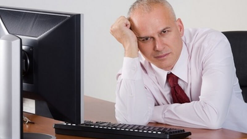 Müder, abgeschlagener Geschäftsmann sitzt auf den Arm gestützt am Schreibtisch