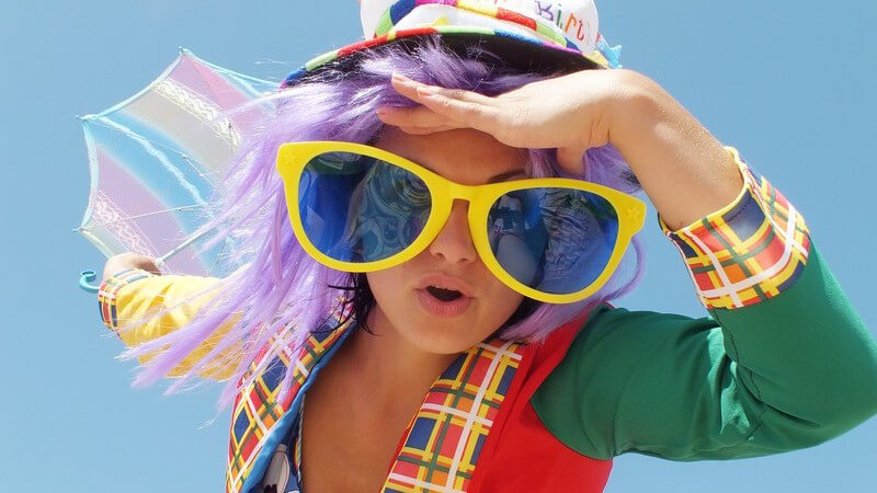 Frau in Sommer-Karnevals-Kleidung: Hut, riesige Brille, Jackett und Bikini