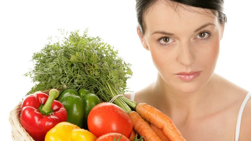 Junge Frau hält Korb mit frischem Gemüse, weißer Hintergrund