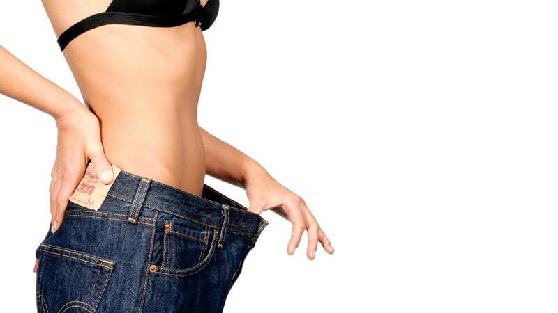 Bauchpartie einer untergewichtigen, dünnen oder sehr schlanken Frau, die eine zu große Jeans trägt, Unterschied