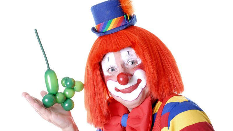 Clown hält Luftballon-Figur in Kamera