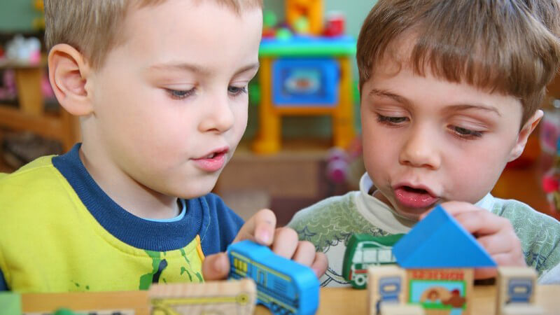 Zwei kleine Jungs beim Spielen mit Holzautos im Kindergarten