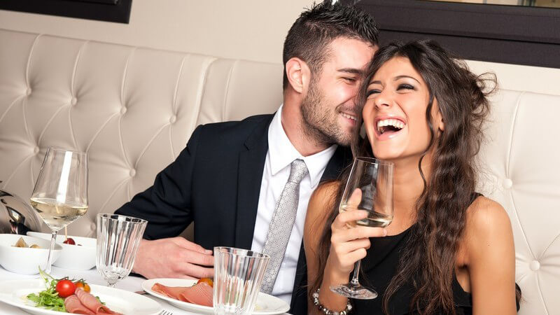 Lächelndes elegant gekleidetes junges Paar im edlen Resturant beim Abendessen