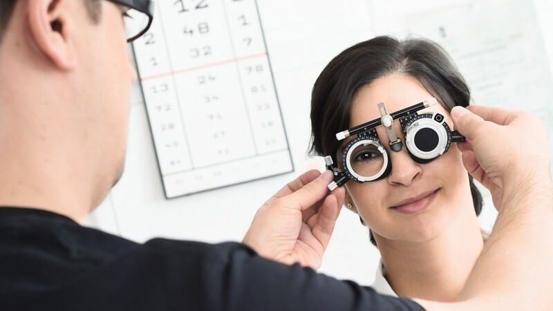 Patientin beim Augenarzt, der ihr eine Messbrille aufsetzt