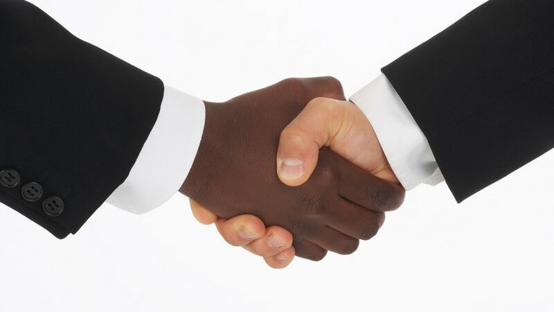 Händeschütteln weiße und farbige Hand zweier Männer im Anzug, weißer Hintergrund