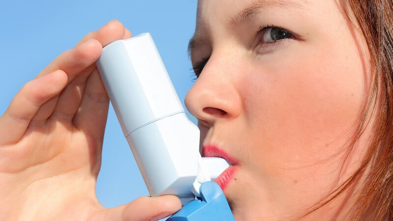 Junge Frau benutzt Asthma-Inhalator