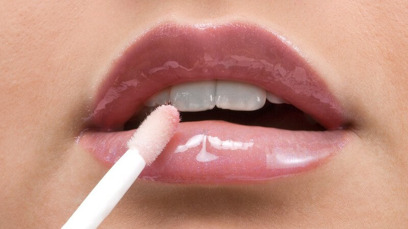 Nahaufnahme Lipgloss wird auf Frauenmund aufgetragen