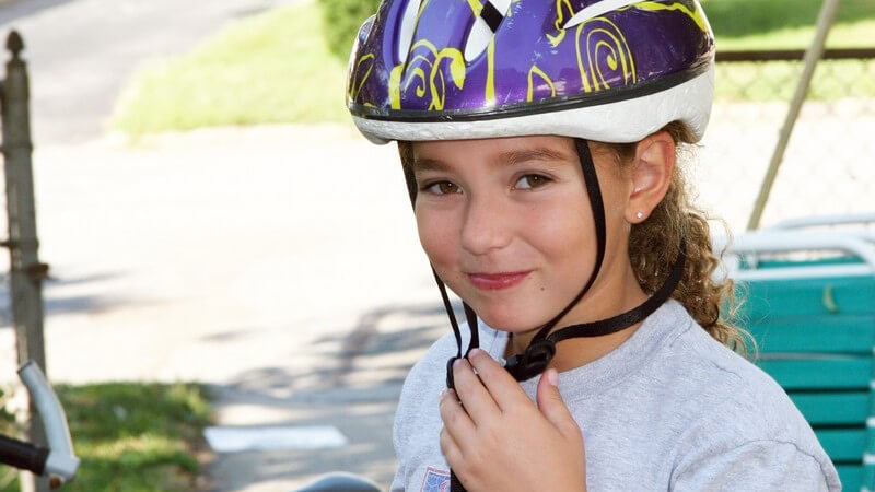 Kleines Mädchen mit Fahrradhelm vor ihrem Fahrrad