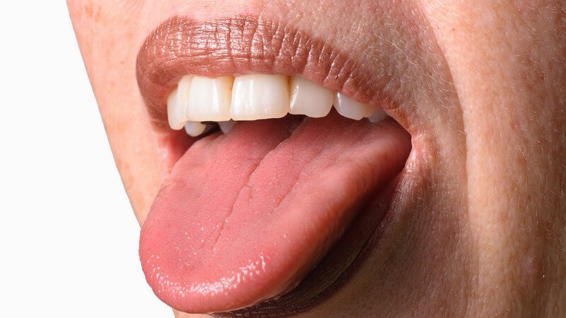Rausgestreckte Zunge einer Frau mit dunklem Lippenstift