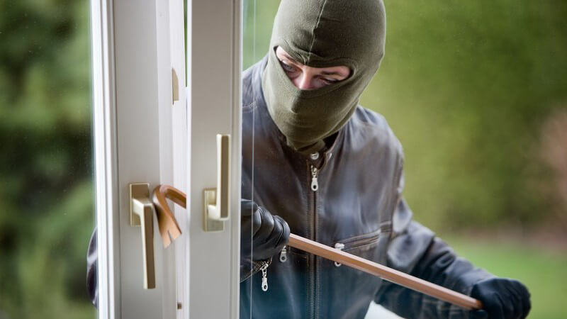 Maskierter Einbrecher versucht mit Brecheisen gekipptes Fenster zu öffnen