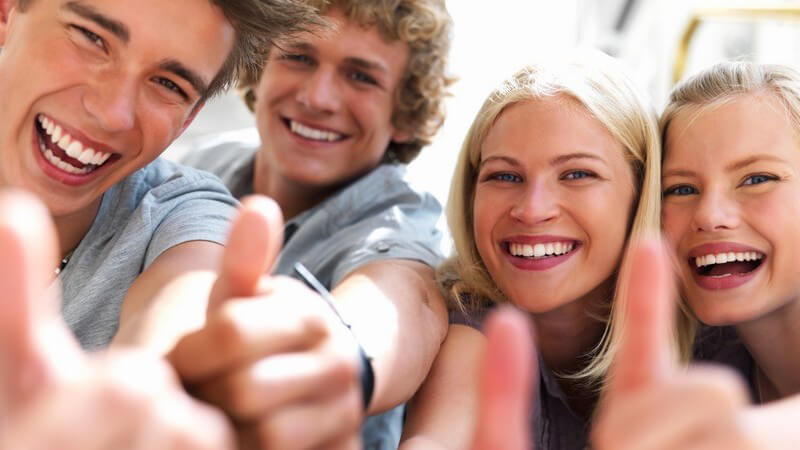 Vier Jugendliche lachen in Kamera, Daumen zeigt nach oben