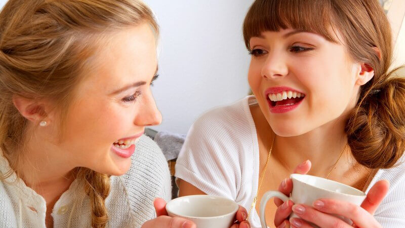 Zwei junge Frauen lachen bei einer Tasse Tee