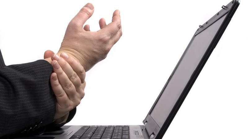 Laptop, Männerhand stützt die andere, die krampfartig gehalten wird