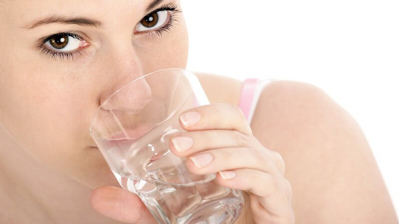 Junge Frau trinkt aus einem Glas Wasser