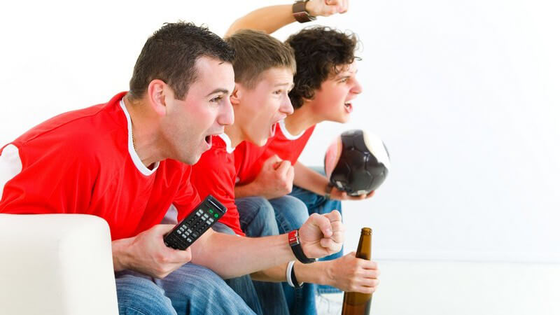 Drei junge Männer auf Couch beim Fußballgucken