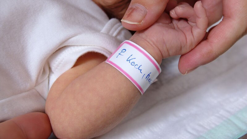 Baby kurz nach der Geburt mit einem Geburtsbändchen am Handgelenk