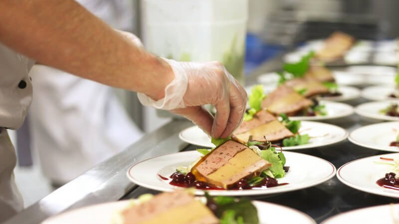 Viele Teller in Restaurantküche werden mit Vorspeise garniert