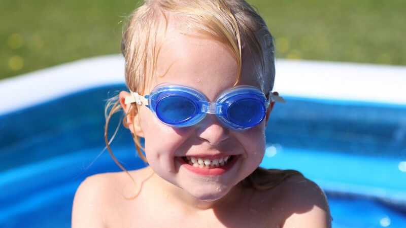 Kleines Mädchen mit Taucherbrille im Planschbecken
