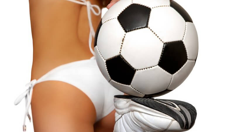 Junge Frau in weißem Bikini und Fußballschuhen mit Fußball