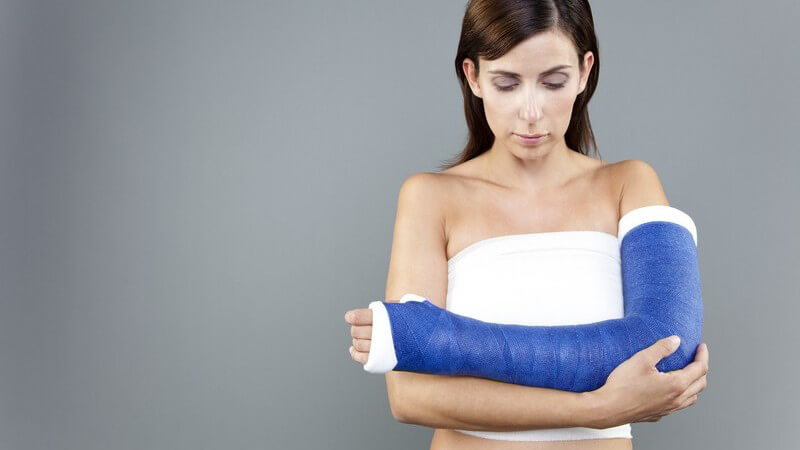 Frau mit gebrochenem Arm, Gips mit blauem Verband