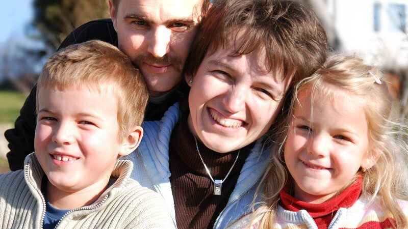 Familienfoto von glücklicher Familie, Vater, Mutter, Tochter, Sohn, lächelnd, bei Sonnenschein