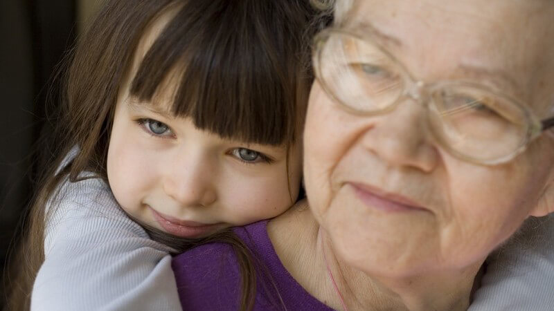 Kleines Mädchen umarmt ihre Großmutter von hinten