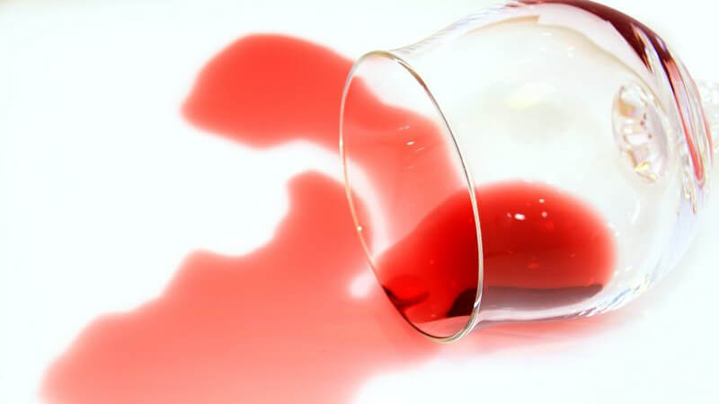 Umgekipptes Glas mit Rotwein auf weißem Hintergrund