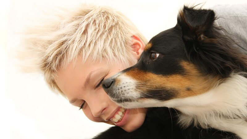Junge blonde Frau mit kurzen Haaren mit ihrem Hund, Gesicht an Gesicht