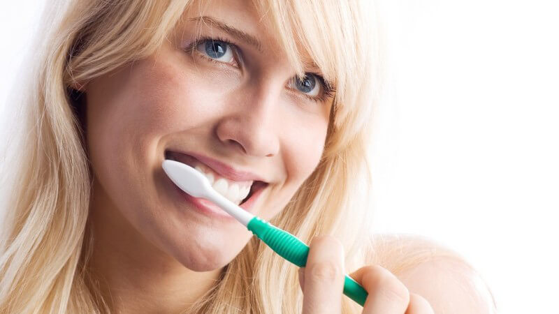Junge Frau beim Zähneputzen, weißer Hintergrund