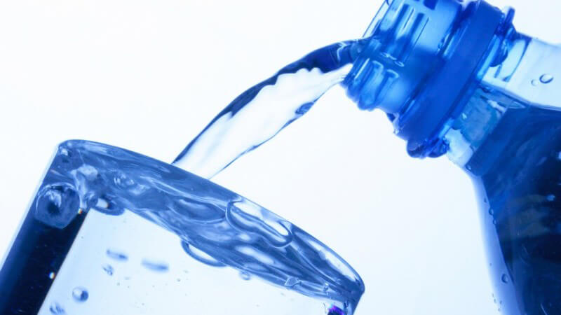 Nahaufnahme Mineralwasser wird aus Plastikflasche in Glas geschüttet