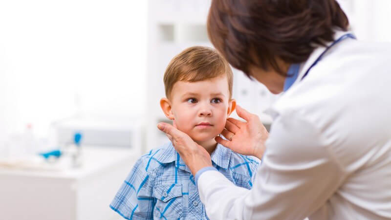 Ärztin tastet Hals eines kleinen Jungen ab