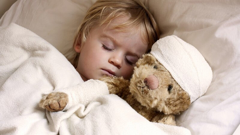 Kleiner Junge schläft neben Teddybär im Bett