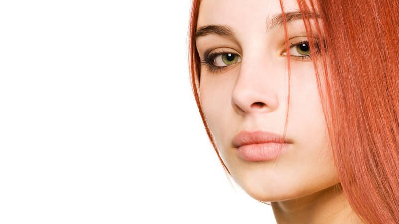 Gesichtsportrait, junge Frau mit roten Haaren schaut seitlich in die Kamera