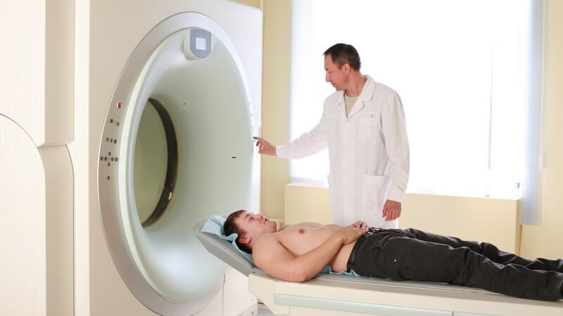 Patient wird von Arzt in Kernspin-Tomografen geschoben