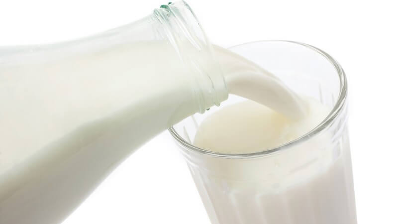 Milchflasche schüttet Milch in ein Glas