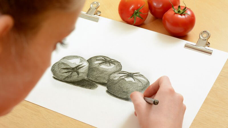 Schülerin beim Zeichnen, sie zeichnet Tomaten