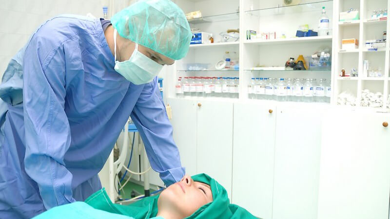 Chirurg im Operationssal über Patient gelehnt
