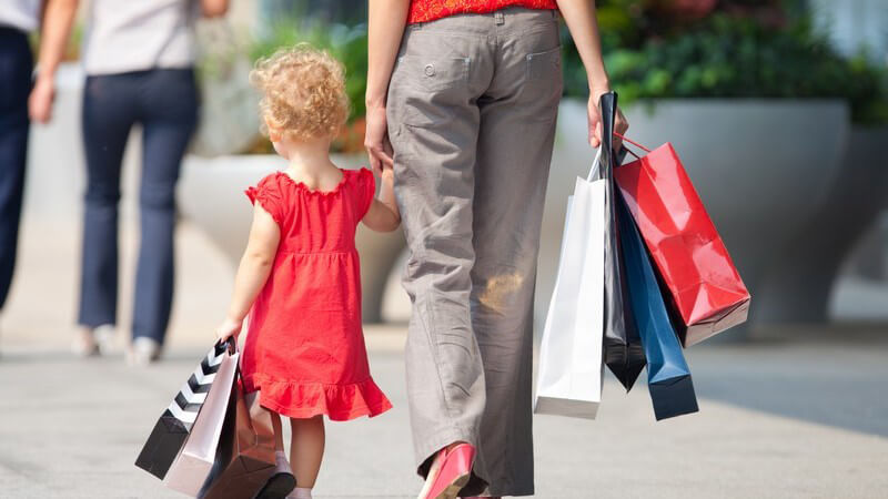 Mutter und kleine Tochter in rotem Kleid Hand in Hand, Shoppen
