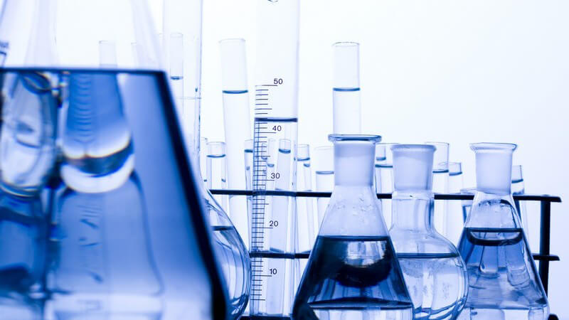Mehrere Reagenzgläser auf Labortisch mit durchsichtiger, blau schimmernder Flüssigkeit