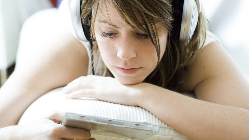 Nahaufnahme junge Frau liegt auf Couch, hört Musik über Kopfhörer