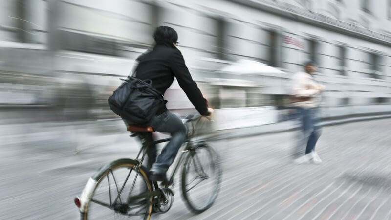 Fahrradfahrer in der Stadt fährt entlang einer Häuserwand